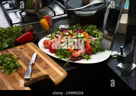 Tritare vari ortaggi freschi nella cucina, interni colorati close-up Foto Stock