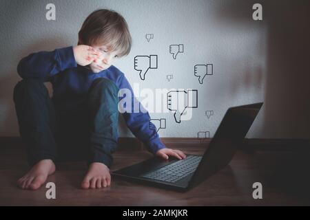 Concetto di bullismo cibernetico - ragazzo depresso con blocco note e commenti negativi Foto Stock