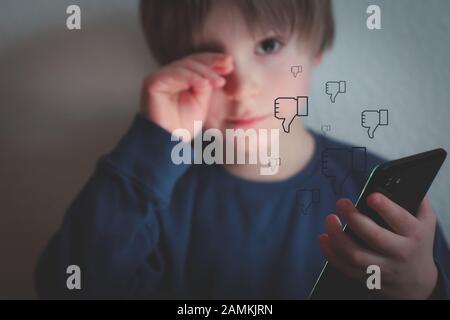 Cyber bullismo concetto - ragazzo depresso con telefono e commenti negativi Foto Stock