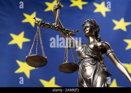 Statua della dea bendata della giustizia Themis o Justitia, contro una bandiera europea, come concetto giuridico Foto Stock