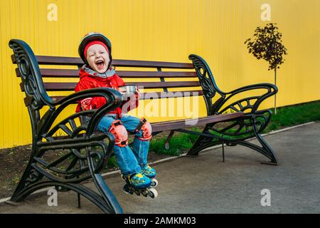 bambino dopo aver pattinando riposato su una panchina Foto Stock