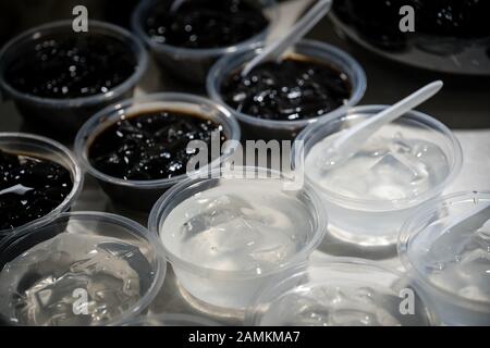 Ciotole trasparenti in plastica con dolce gelatina dessert cinese su un tavolo buffet self-service per la colazione in un ristorante Foto Stock