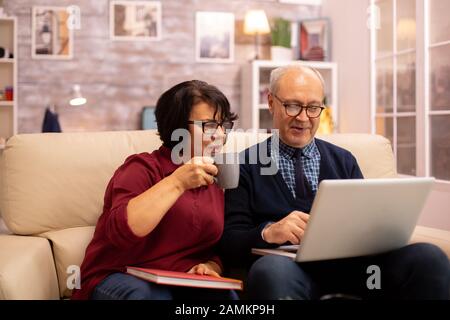 Nonna e nonno usando un computer portatile per chattare con i loro nipoti. Le persone anziane usando tecnologie moderne Foto Stock