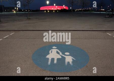 Segno pedonale su grande parcheggio vuoto prima della semifinale della Champions League FC Bayern Monaco - Real Madrid Champions. Sullo sfondo lo stadio rosso illuminato. [traduzione automatizzata] Foto Stock