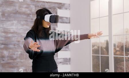 Bella casa designer femminile utilizzando occhiali realtà virtuale all'interno di un appartamento vuoto. Foto Stock