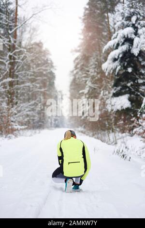 Vista posteriore del corridore femminile che lega i suoi shoelaces Foto Stock