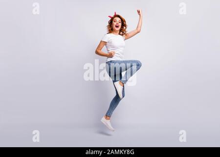 Lunghezza piena dimensione del corpo vista di lei bella attraente bella fortunato Allegro vivace ragazza jumping indossando abiti casual gioia divertimento conseguimento Foto Stock