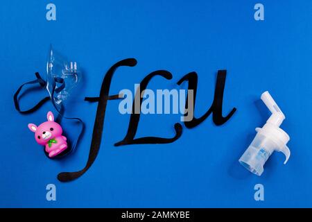 maschera tubiera nebulizzatore e cavo tubolare trasparente e la parola influenza su sfondo blu, raffreddori per bambini. Foto Stock