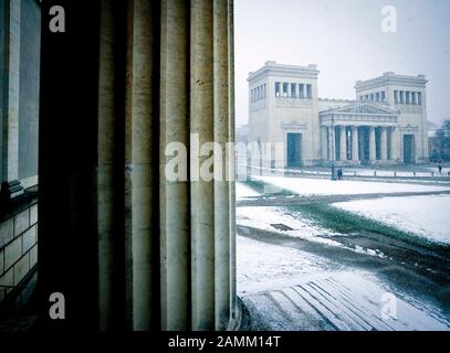 La Königsplatz nella neve: In primo piano una colonna e la scala innevata della Collezione statale di antichità classiche, sullo sfondo la Propylaea. [traduzione automatizzata] Foto Stock