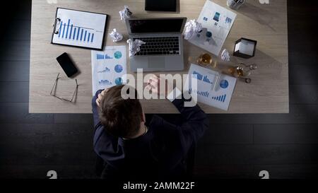 Uomo d'affari seduto al suo ufficio pensando a bere alcol, depressione Foto Stock