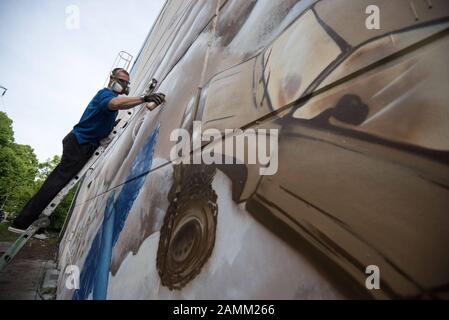 Gli artisti Graffiti abbelliscono il muro esterno del nuovo workshop sui rifugiati nella sistemazione dei richiedenti asilo nell'ex caserma bavarese a Heidemannstraße 60 con la loro arte spray [traduzione automatizzata] Foto Stock