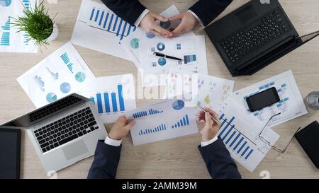 Due uomini che controllano i diagrammi di affari, che discutono il rapporto finanziario, brainstorming Foto Stock