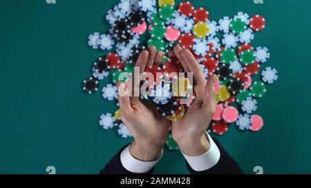 Uomo che detiene una manciata di chip di poker, vince piccola fortuna in casinò, gioco d'azzardo Foto Stock