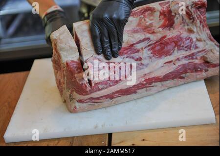 Un macellaio taglia un pezzo di carne nel suo negozio nel Schrannenhalle. [traduzione automatizzata] Foto Stock