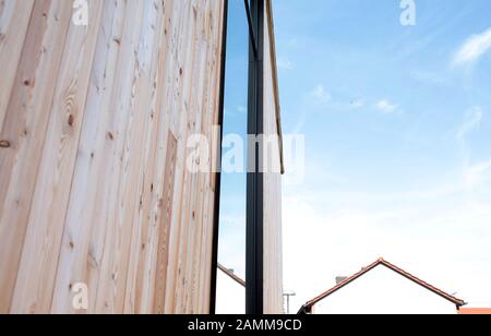 Nuova costruzione del centro verde con materiali edili naturali (vetro e legno) a Puch. Sullo sfondo il timpano di una casa indipendente. [traduzione automatizzata] Foto Stock