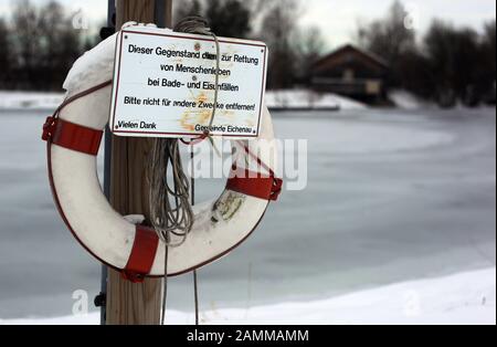 Strato di ghiaccio pericolosamente sottile sul lago balneabile Eichenauer. L'immagine mostra un pneumatico di salvataggio sulla banca. [traduzione automatizzata] Foto Stock