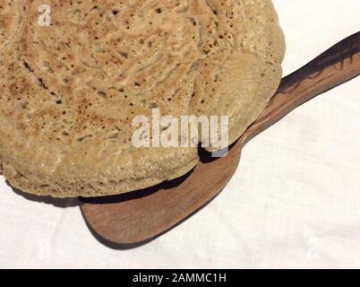 Pane piatto di injera fatto da farina di teff. Teff, chiamato anche mulino nano, appartiene alla famiglia dell'erba dolce. La gamma naturale è in Etiopia ed Eritrea, ma la specie è coltivata anche in altre zone tropicali e subtropicali. I semi sono privi di glutine e ricchi di acidi grassi essenziali. Questo tipo di miglio è il grano più importante in Etiopia. Viene trasformato in pane e birra piatti o viene utilizzato anche come mangime per animali [traduzione automatizzata] Foto Stock