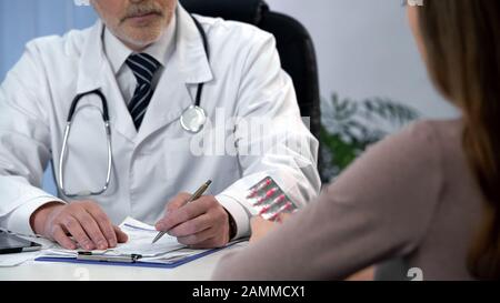 Il medico di famiglia che prescrive il trattamento e che dà le pillole al paziente, l'assistenza sanitaria Foto Stock