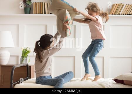 Madre felice e figlia piccola che si divertono, giocando con i cuscini Foto Stock