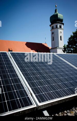 Impianto fotovoltaico sul tetto di una casa, sullo sfondo una chiesa. [traduzione automatizzata] Foto Stock