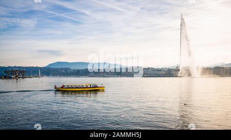 Panorama del Lago di Ginevra con il famoso Jet d'Eau o jet d'acqua e una piccola barca gialla a navetta in Ginevra Svizzera Foto Stock