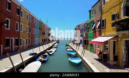 Case colorate e barche ormeggiate lungo il canale sull'isola di Burano, locali in strada Foto Stock