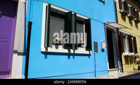 Scatole postali ordinate appese vicino a porte dipinte di colori vivaci di case colorate Foto Stock