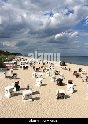 Vista dal ponte sul mare Heringsdorf sulla spiaggia sabbiosa del Mar Baltico con molte sedie a sdraio in condizioni di sole e le nuvole drammatiche sull'isola Usedom nel Mecklenburg Vorpommern, Germania, Europa. [traduzione automatizzata] Foto Stock