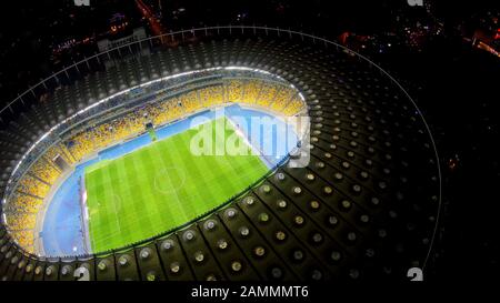 Giocatori di calcio su grande campo stadio, partita di sport, punto di riferimento illuminato Foto Stock