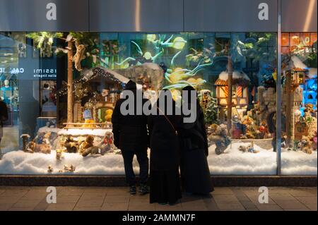 I turisti arabi hanno la vista sulle decorazioni natalizie nella vetrina di Galeria Kaufhof a Marienplatz. [traduzione automatizzata] Foto Stock