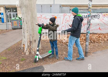 Ragazzo di dieci anni in sella a uno scooter elettrico a noleggio Lime, Karlsplatz, Vienna, Austria. Foto Stock