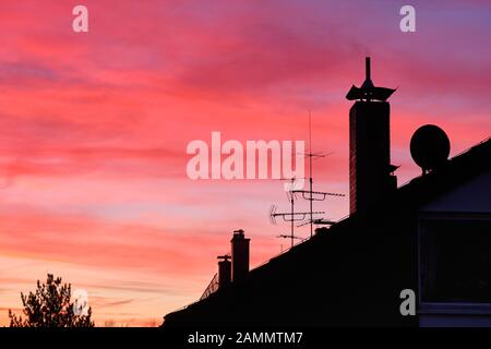 Bella rosa alba cielo sopra i tetti con antenne e camini nella città di Norimberga in Germania nel mese di gennaio Foto Stock