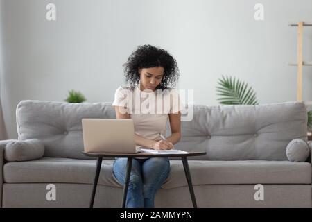 Donna africana seduta al tavolo del caffè con penna scritta Foto Stock