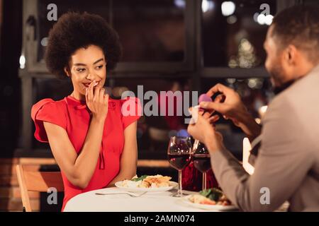 Afro Guy Che Mostra Fidanzato Fidanzato Anello Di Proporre In Ristorante Foto Stock