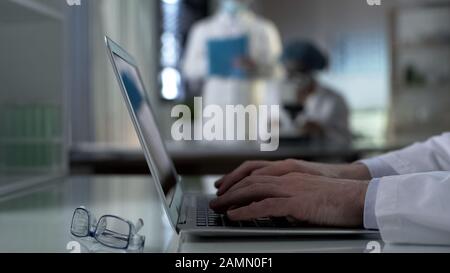 Gli scienziati che utilizzano i risultati degli esperimenti di battitura a macchina su laptop, lavorando al progetto in laboratorio Foto Stock