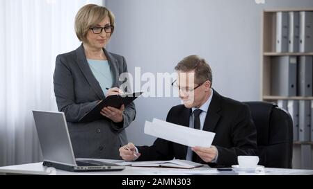 Il capo maschio soddisfatto felice con il rapporto corretto da ragioniere della donna, buon lavoro fatto Foto Stock