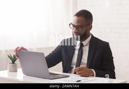 Giovane manager che lavora con il computer portatile nel suo ufficio Foto Stock
