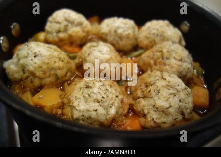 Grande Nero Pan casereccio Brodo vegetale & Otto Herby gnocchi cottura su un piano cottura a gas. Foto Stock