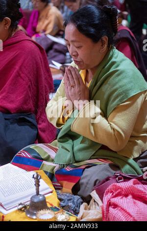 Una devota buddista che prega e medita mentre si siede con le mani giunte. In un tempio di Queens, New York City. Foto Stock