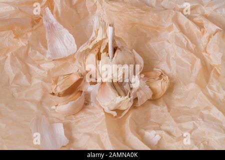 Aglio biologico su carta kraft rustico. Foto Stock