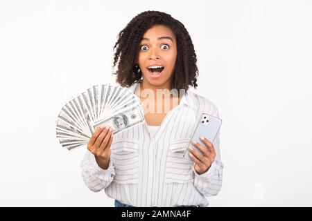 Donna nera eccitata che detiene denaro e iPhone 11 Foto Stock