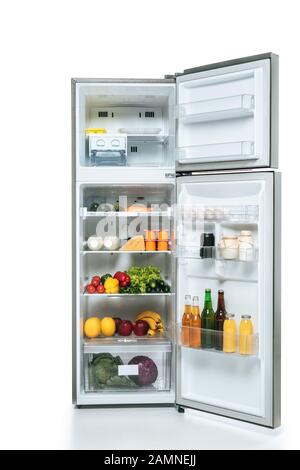 frigo aperto e freezer con cibi freschi su scaffali isolati su bianco Foto Stock