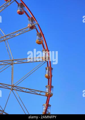 Immagine verticale con primo piano di sezione di colore rosso brillante, giallo e bianco ruota panoramica o osservazione con poche cabine vuote. Nessuna gente. Clea Foto Stock