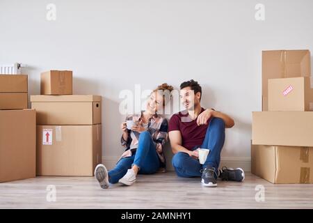 Felice coppia con caffè tazze rilassante nella loro nuova casa Foto Stock