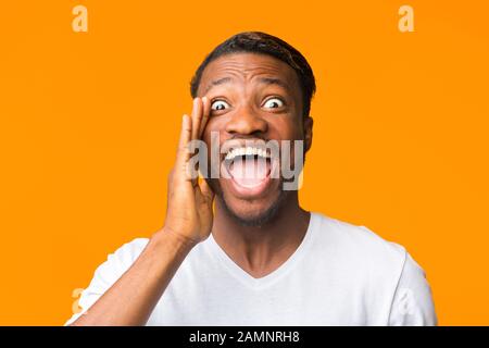 Funny Afro Guy Screaming Holding Mano Vicino Bocca In Studio Foto Stock