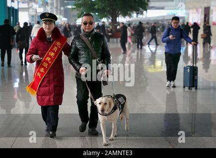 (200114) -- ZHENGZHOU, 14 gennaio 2020 (Xinhua) -- un membro del personale ferroviario aiuta il cognome dei passeggeri ipovedenti Jin e il suo cane guida Xiaoqi a prendere un treno alla stazione ferroviaria di Zhengzhoudong a Zhengzhou, nella provincia centrale cinese di Henan, 14 gennaio 2020. Il passeggero ipovedenti sornamed Jin avrebbe preso un treno ad alta velocità con il suo cane guida Xiaoqi il martedì alla stazione ferroviaria di Zhengzhoudong. Ha fatto una telefonata alla stazione ferroviaria per assistenza. Il personale della stazione ferroviaria ha immediatamente elaborato un piano per assicurarsi che il passeggero e il suo cane guida abbiano un viaggio comodo e sicuro con Foto Stock