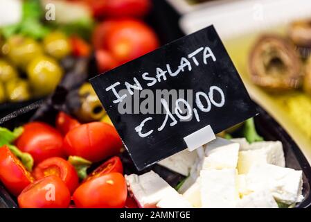 Macro closeup di insalata confezionata con pomodori, olive e formaggio feta nella famosa Firenze Italia Firenze Centrale mercato con segno di spesa Foto Stock