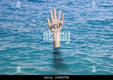 Parola aiuto scritto sul palmo di una mano affondamento nell'acqua dell'oceano. Annegamento di emergenza della persona, guasto e concetto di aiuto Foto Stock