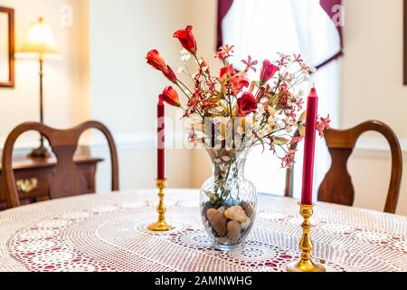 Tavolo da pranzo con antiche candele retro rosso vintage in casa camera da letto con luce brillante dalle finestre e fiori in vaso in camera Foto Stock