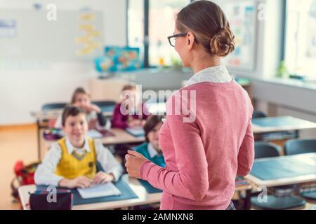 Insegnante con i suoi studenti in classe alla scuola elementare Foto Stock